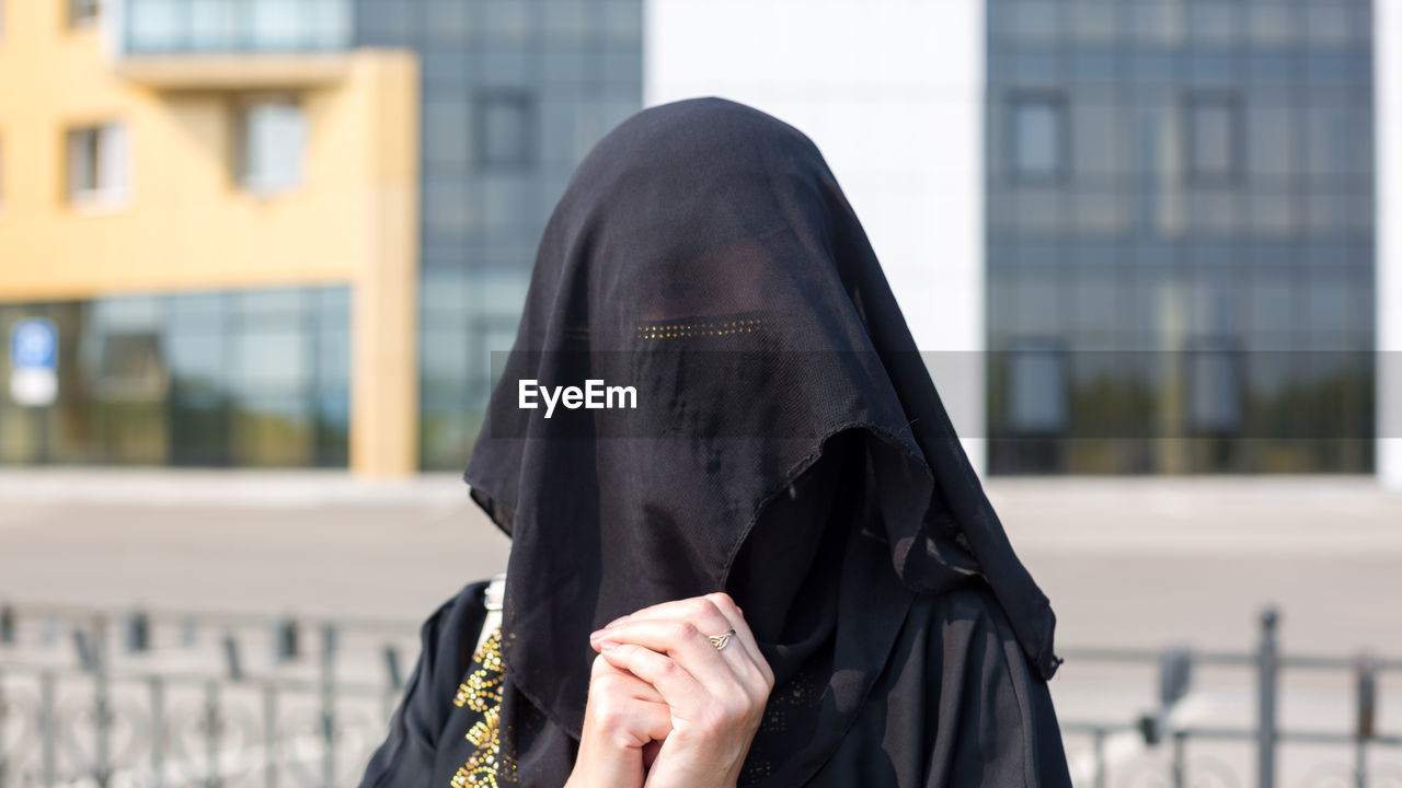 Portrait of muslim woman in national clothes covering her face in a european city.