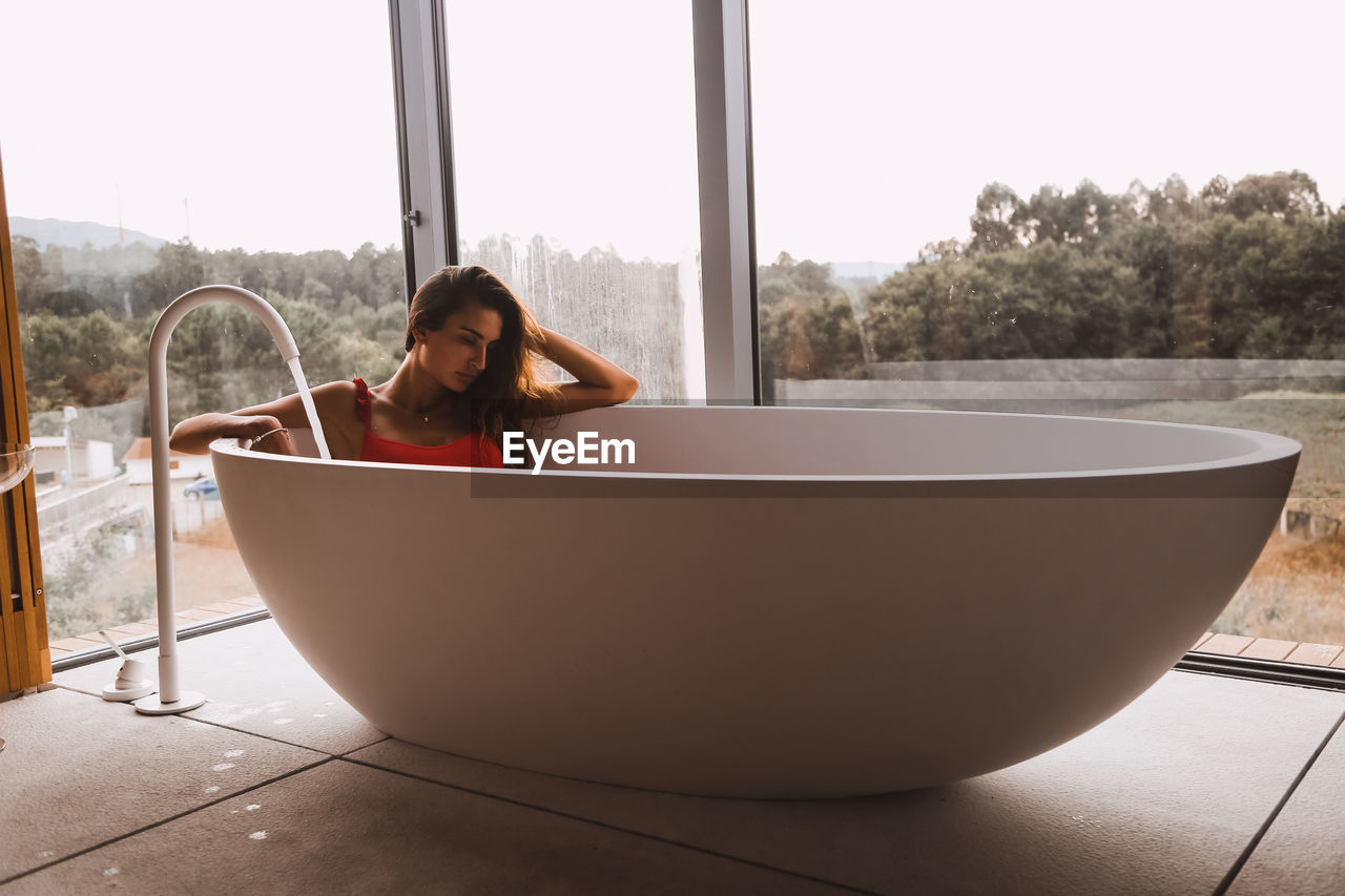 Woman sitting in bathtub at bathroom