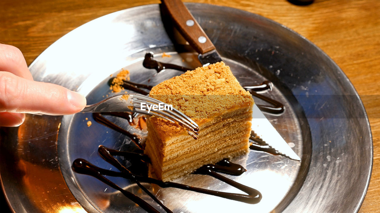 Cropped hand holding fork over dessert