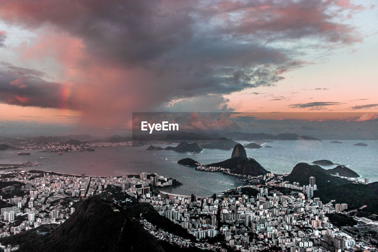 Aerial view of townscape by sea against sky during sunset