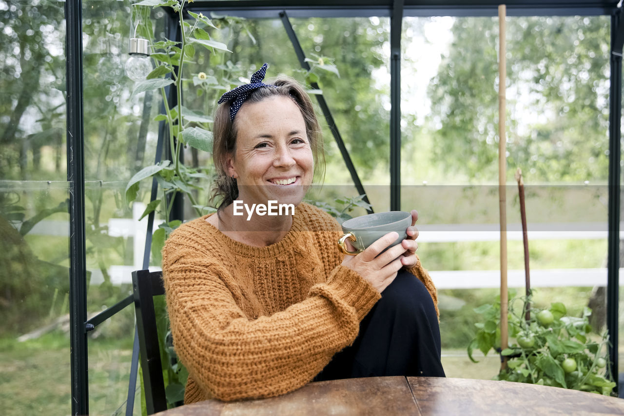 Woman having coffee in greenhouse