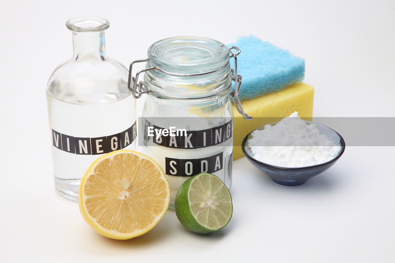Baking soda in the glass container with vinegar and half  slice of lemon  and lime
