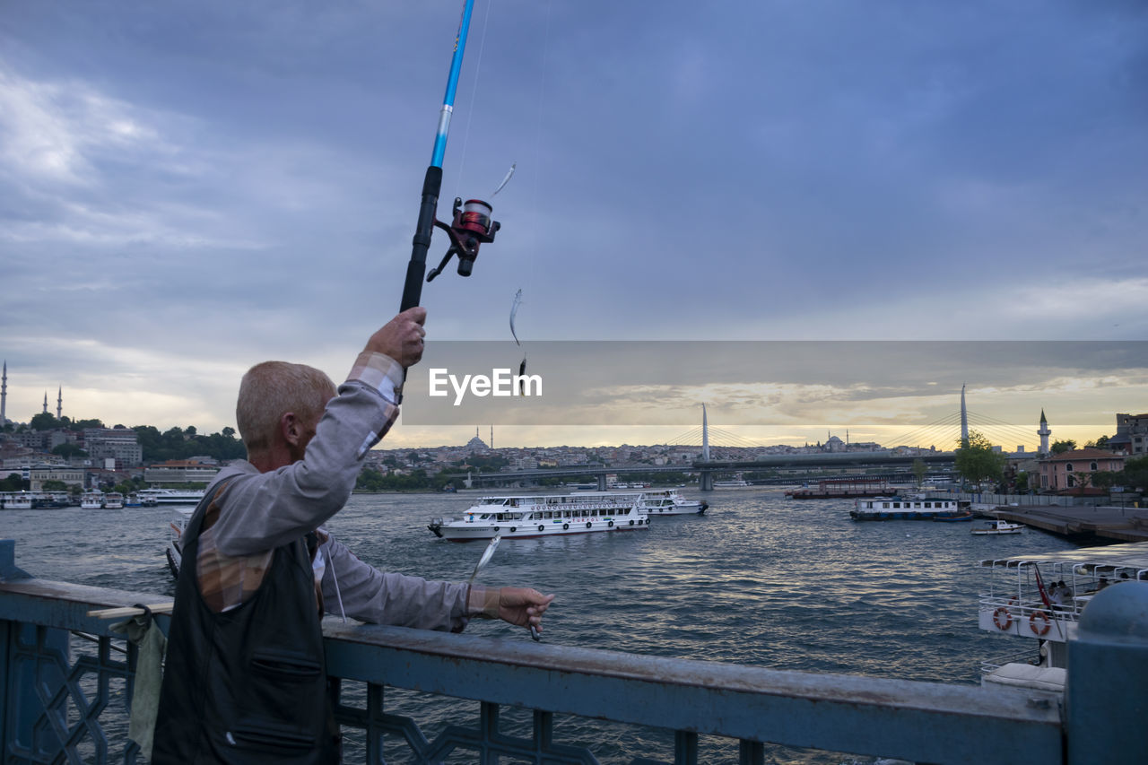 MAN ON BOAT AGAINST SKY