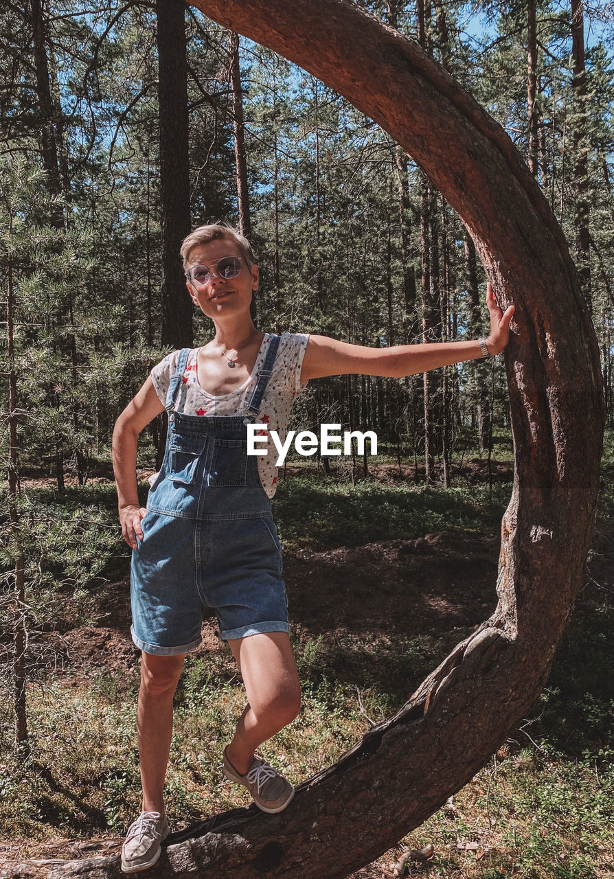 Full length portrait of smiling young woman in forest