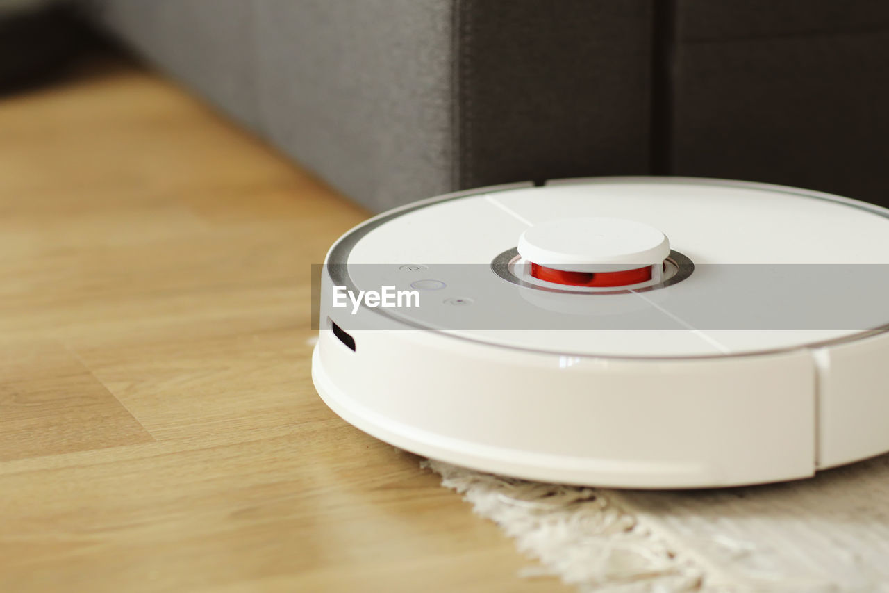 Robot vacuum cleaner performs automatic cleaning of the apartment at a certain time. white robot 