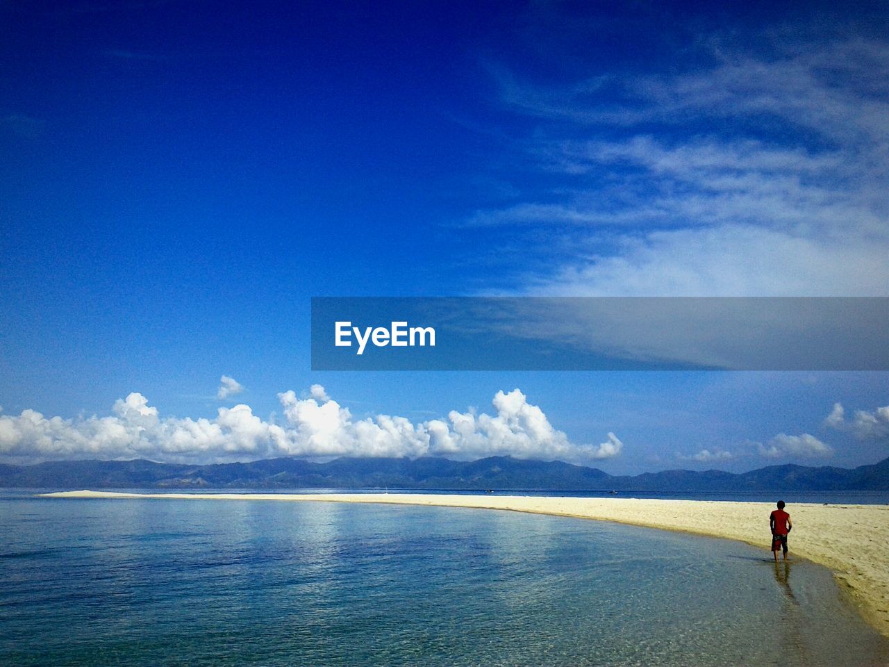 Rear view of man standing on shore against sky at beach