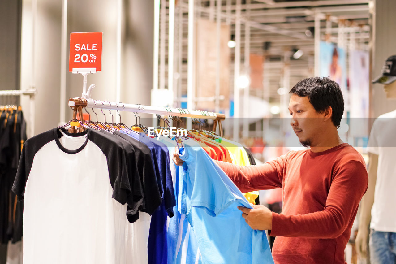 Man looking at clothes while standing in store