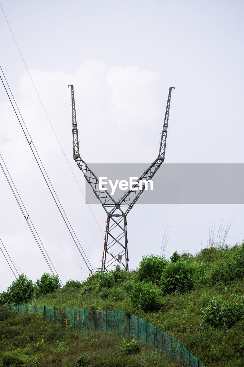 sky, plant, nature, overhead power line, tower, transmission tower, no people, cable, technology, outdoor structure, electricity, cloud, environment, electricity pylon, tree, day, outdoors, landscape, power generation, architecture, line, grass, power supply, built structure, land, power line