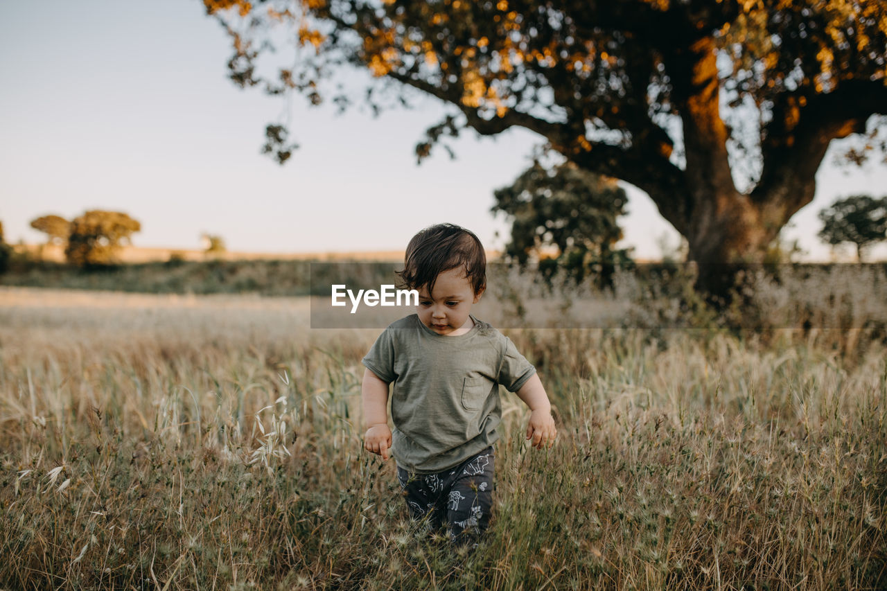 Boy standing on field against sky