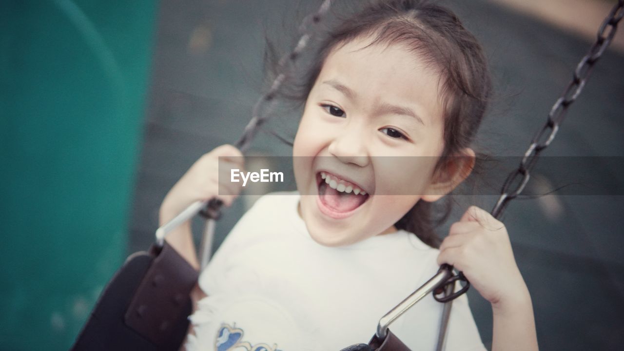 Portrait of smiling girl swinging in playground