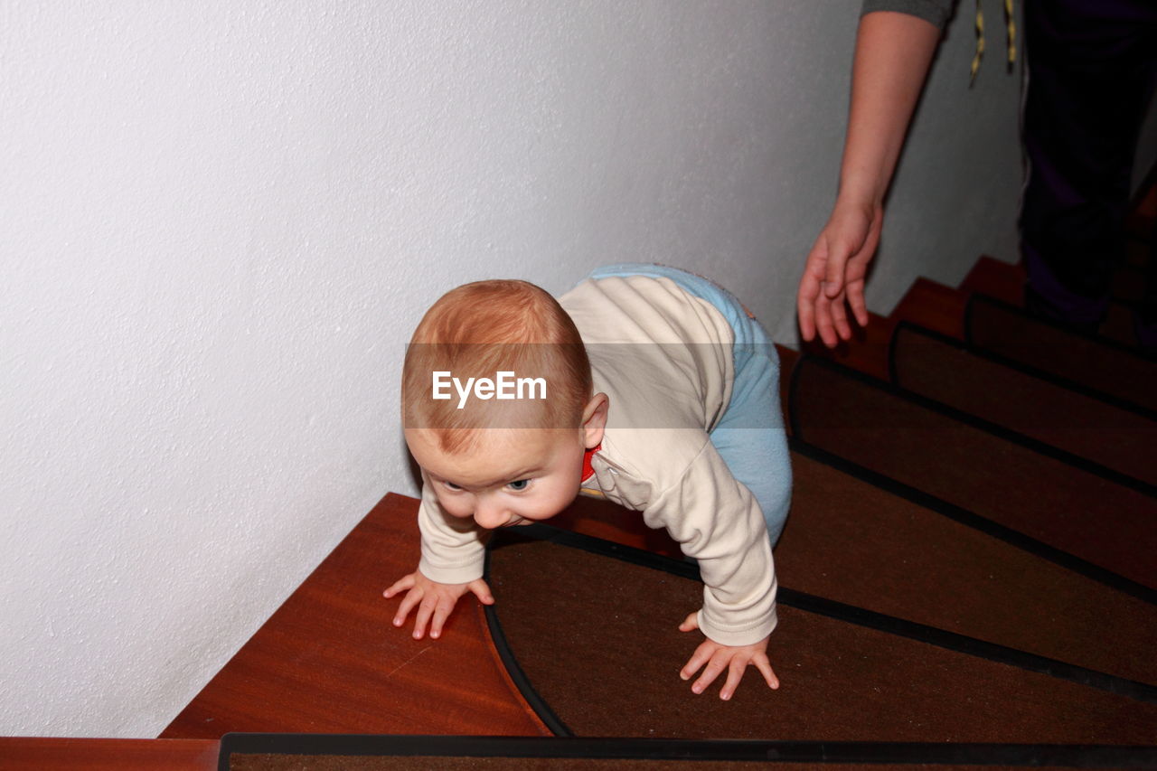 High angle view of baby boy climbing on steps at home