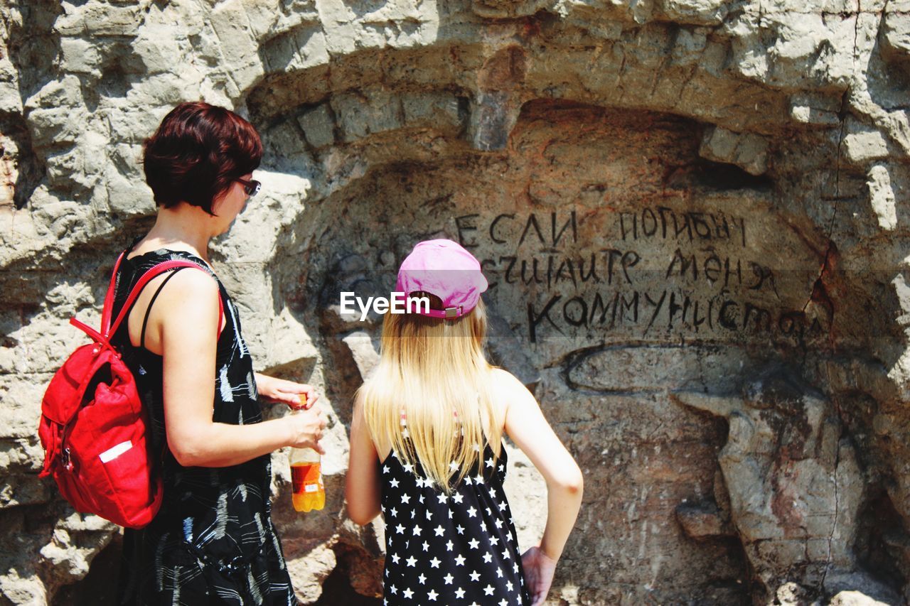 REAR VIEW OF WOMEN STANDING ON WALL