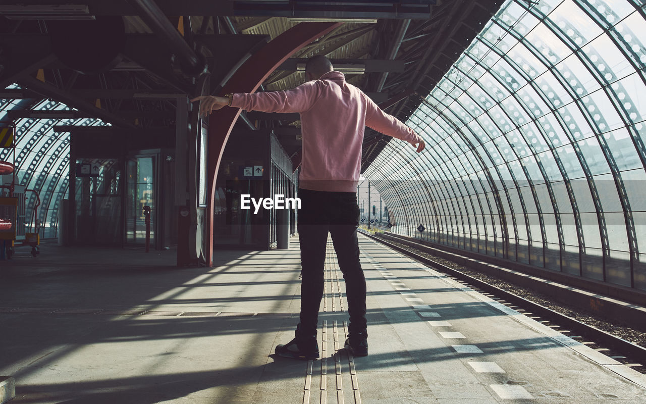 Rear view of man standing on railroad station platform