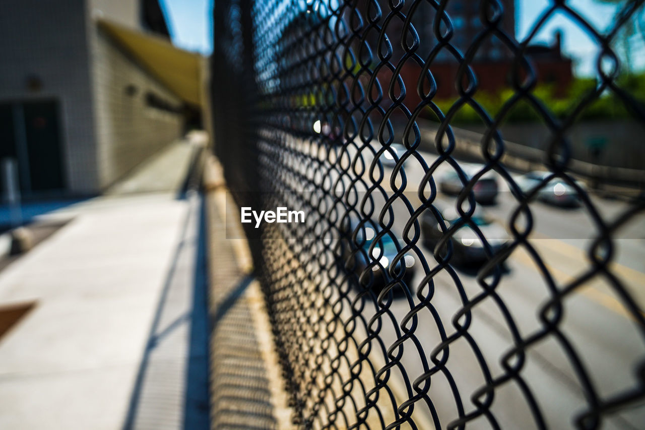 CHAINLINK FENCE AGAINST SKY SEEN THROUGH METAL GRATE