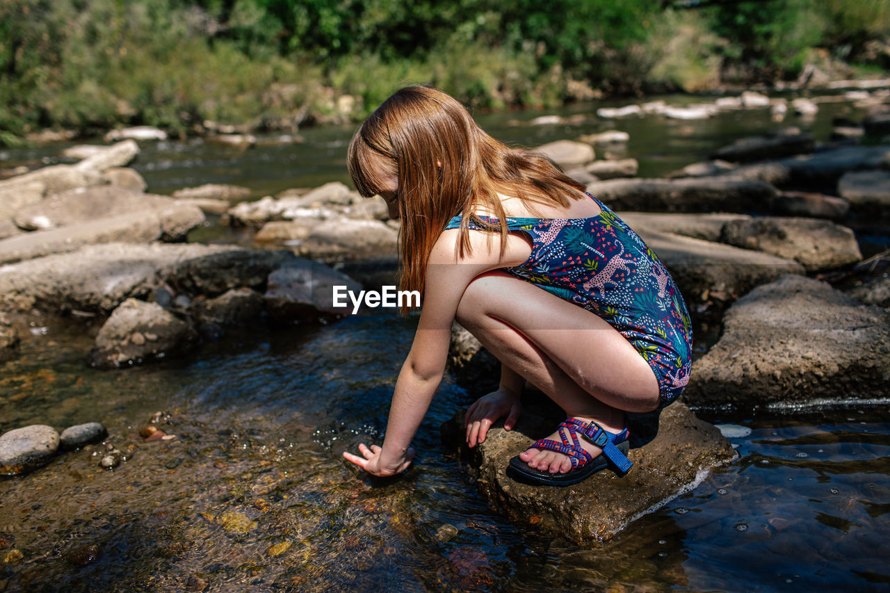 Young girl playing in a shallow stream on a sunny summer day