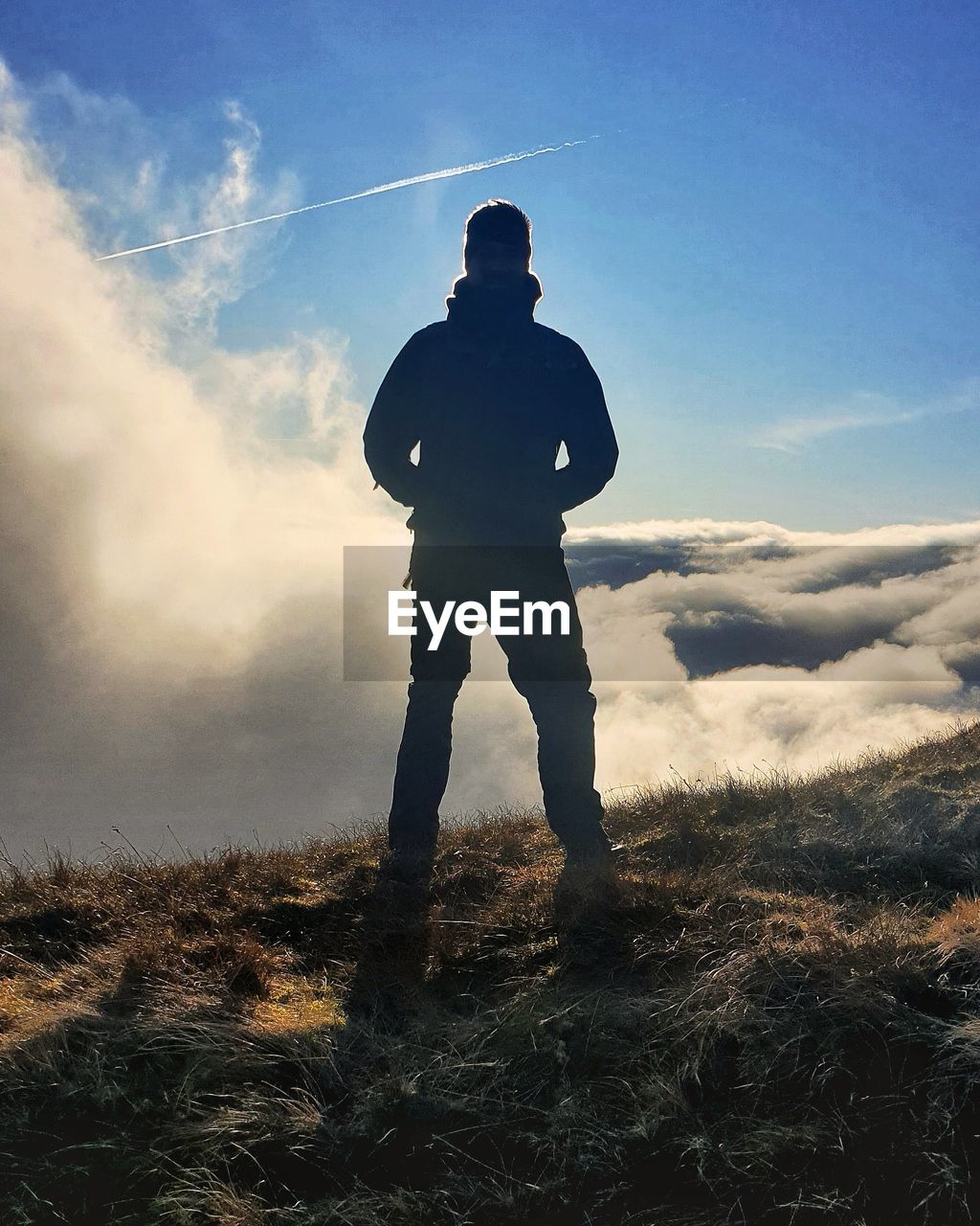 LOW ANGLE VIEW OF MAN STANDING ON FIELD DURING SUNSET