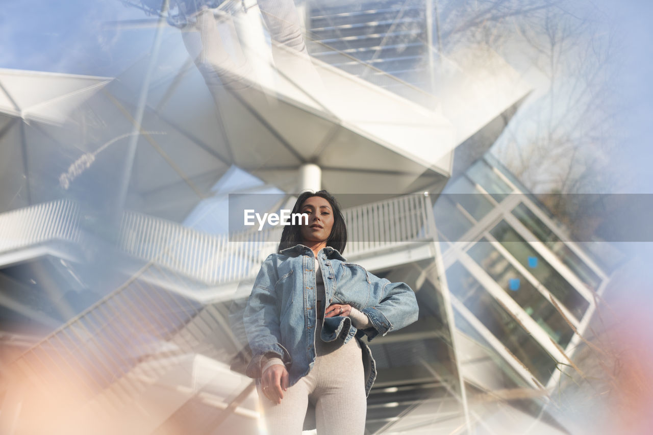 Portrait of young woman standing against building