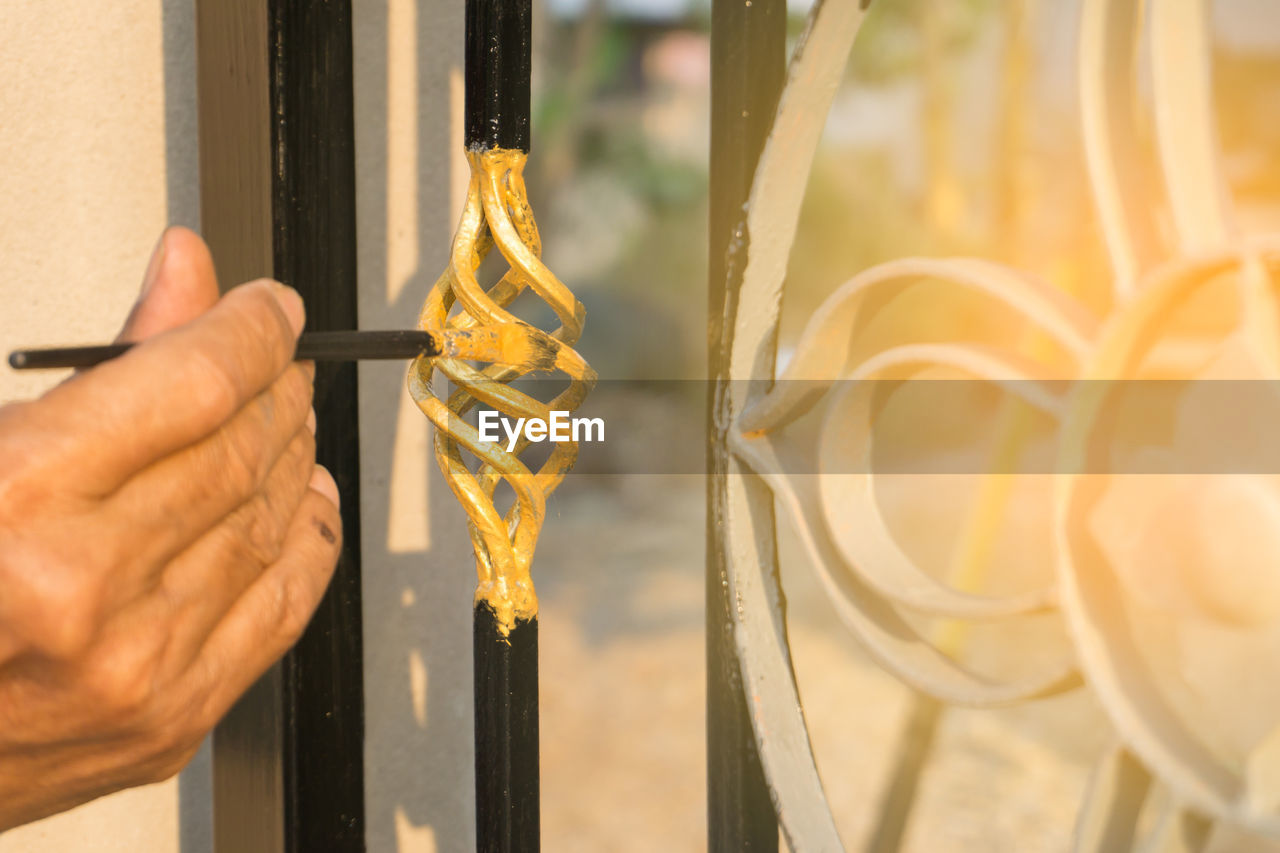 Cropped hand of man painting railing