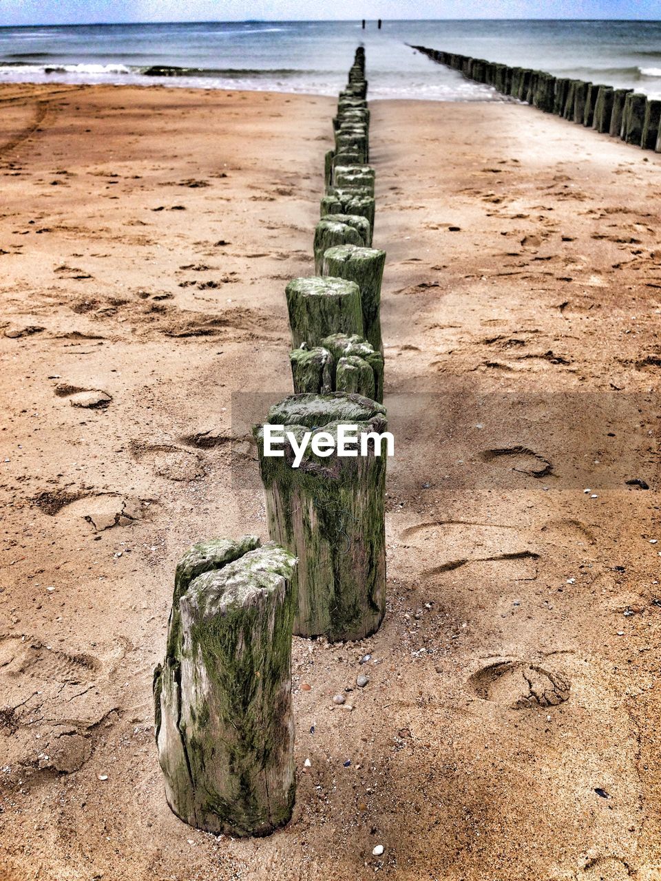 CLOSE-UP OF WOODEN POST ON SAND