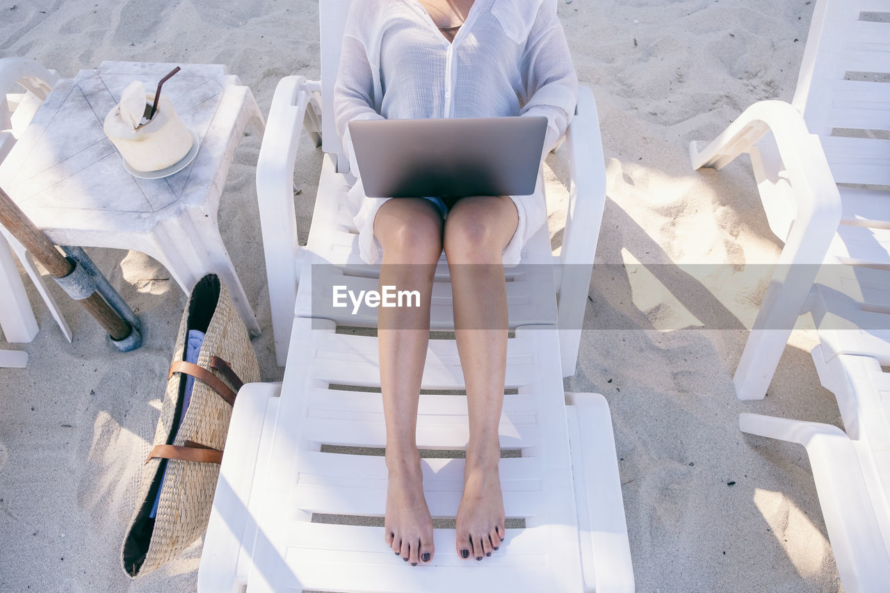 High angle view of woman using laptop while sitting on chair