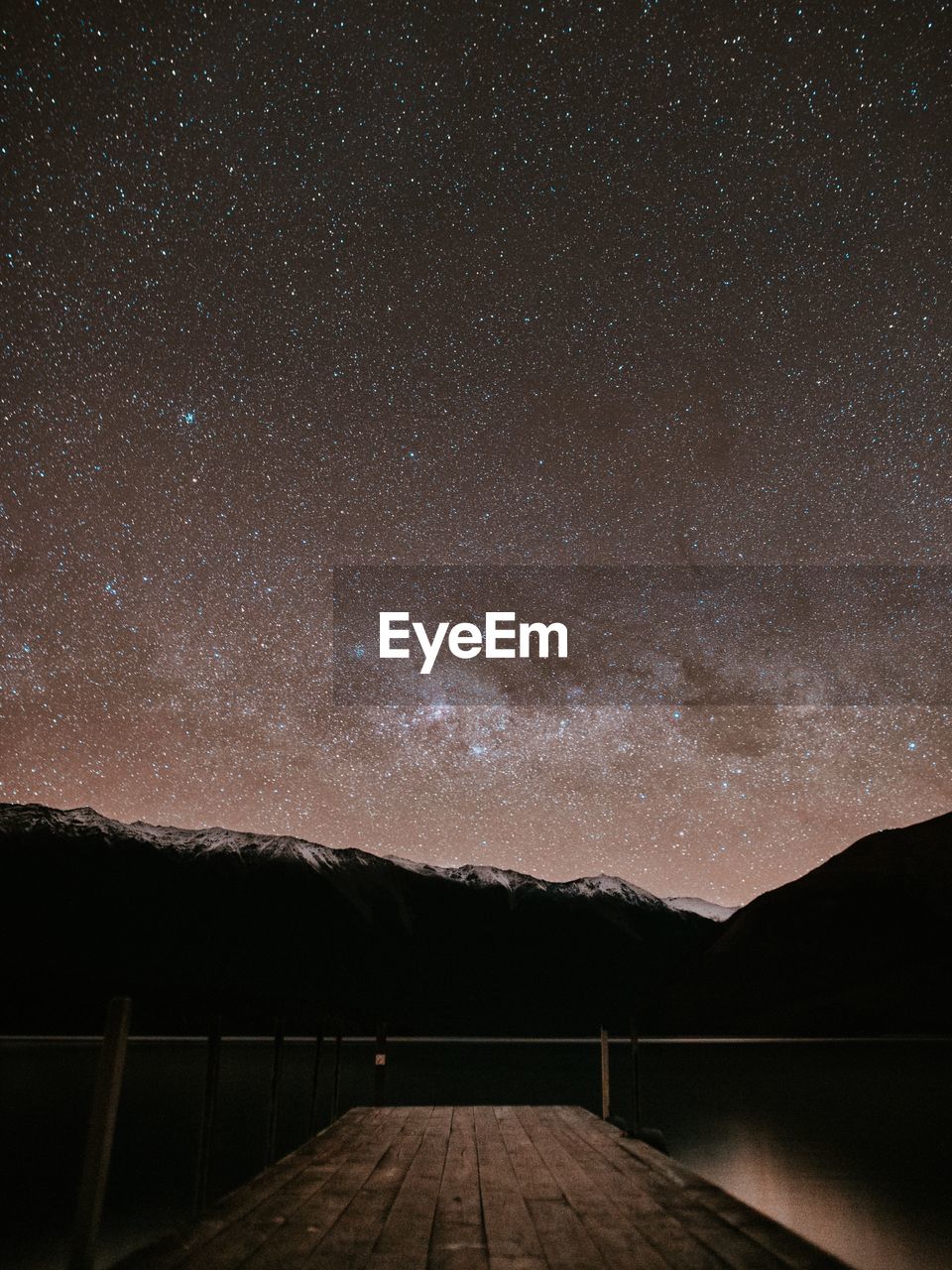 Scenic view of lake and mountains against star field at night