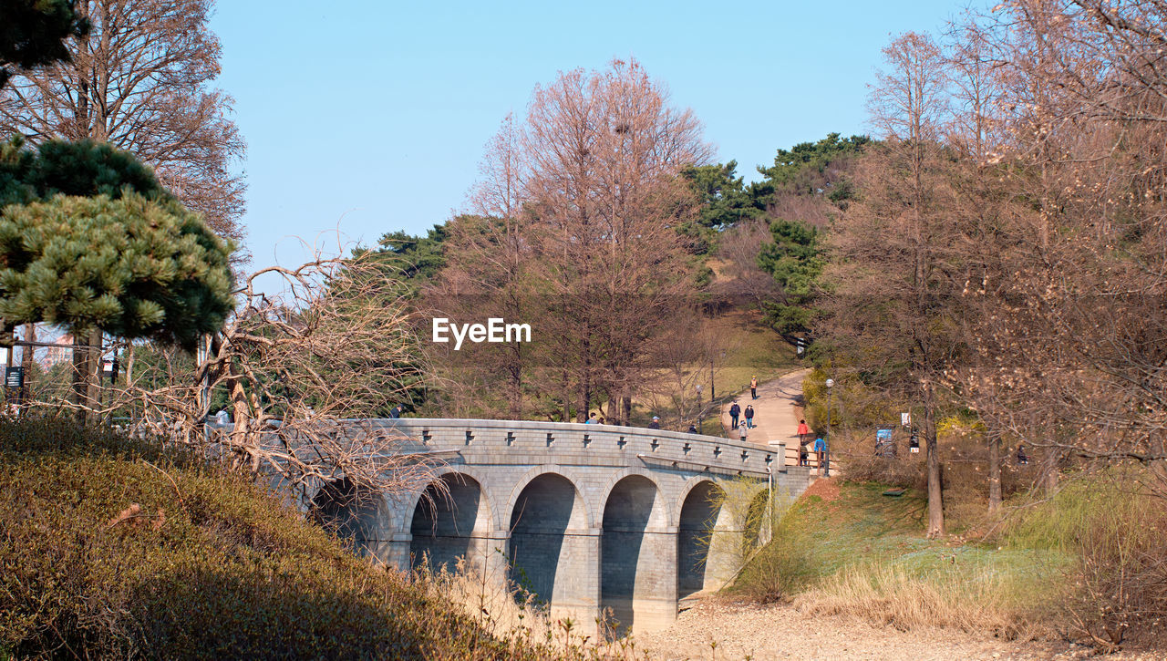 Arch bridge over river against sky during autumn