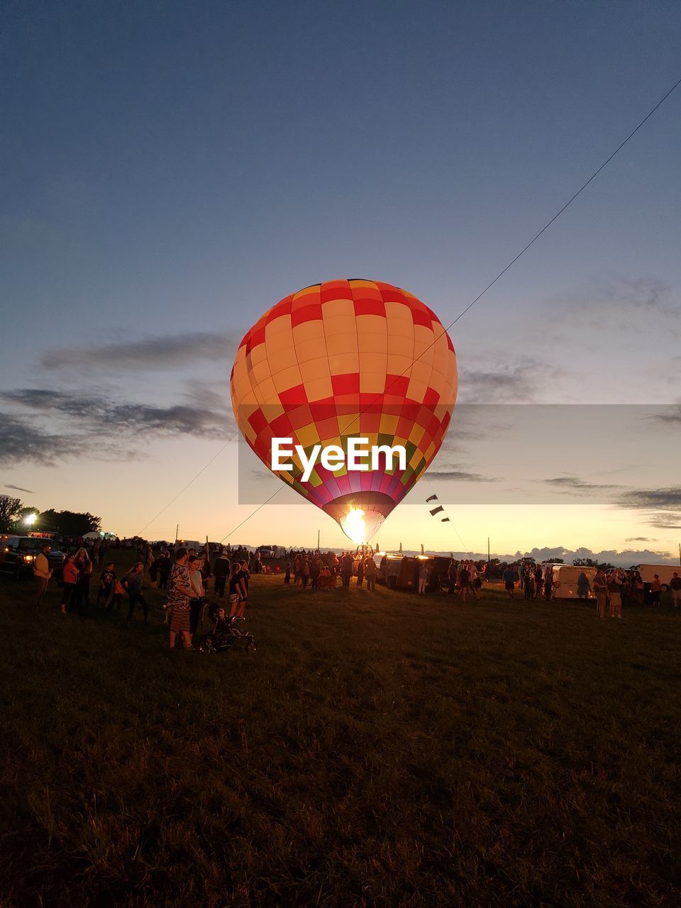 People and hot air balloon against sky during sunset