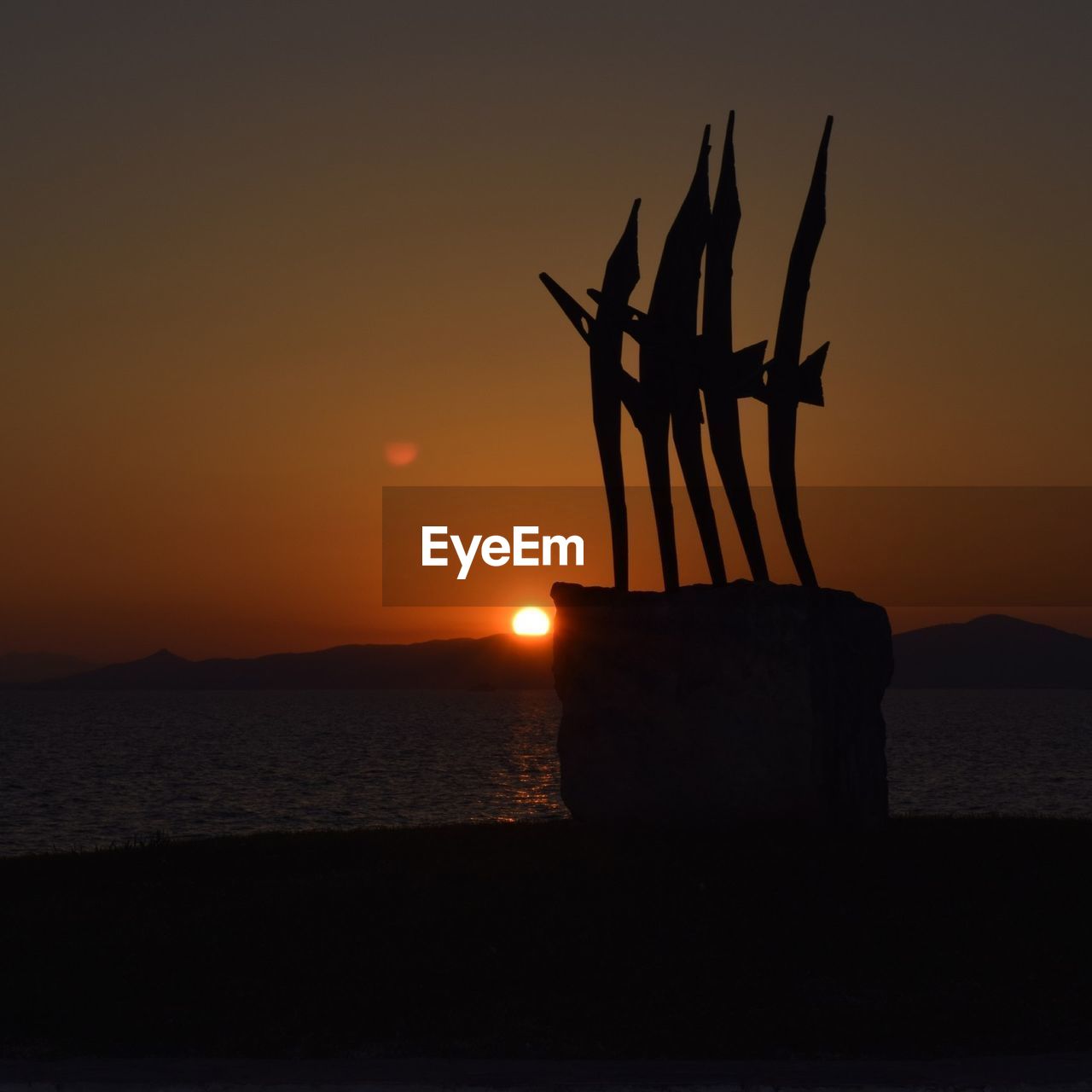 SILHOUETTE TREE AGAINST SUNSET OVER SEA