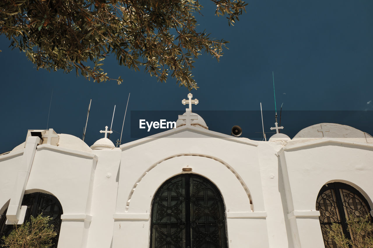 LOW ANGLE VIEW OF WHITE BUILDING AND TREES AGAINST SKY