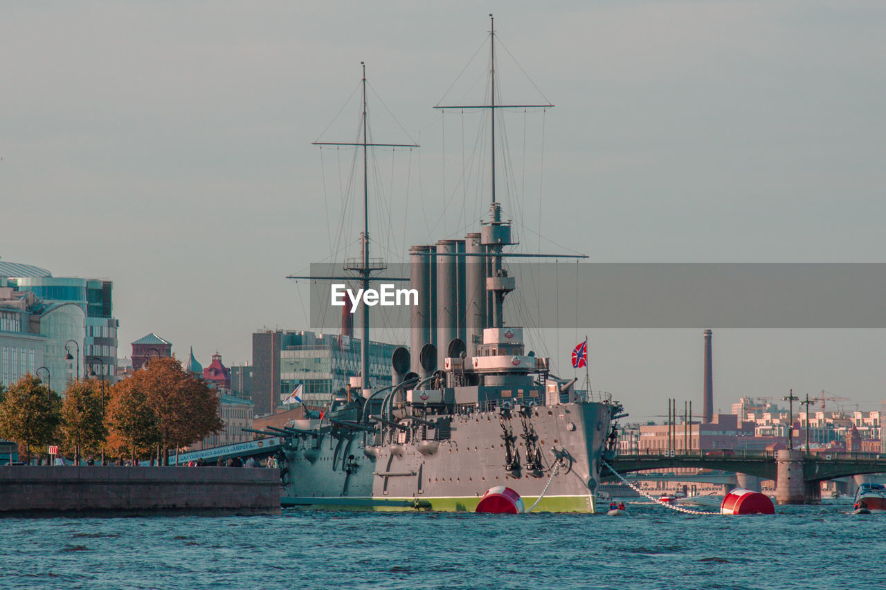 Cruiser aurora in river against buildings in saint-pitersburg