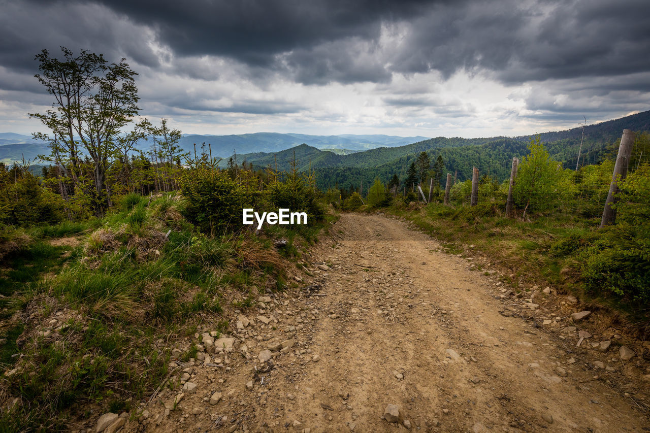 panoramic view of road amidst field against sky