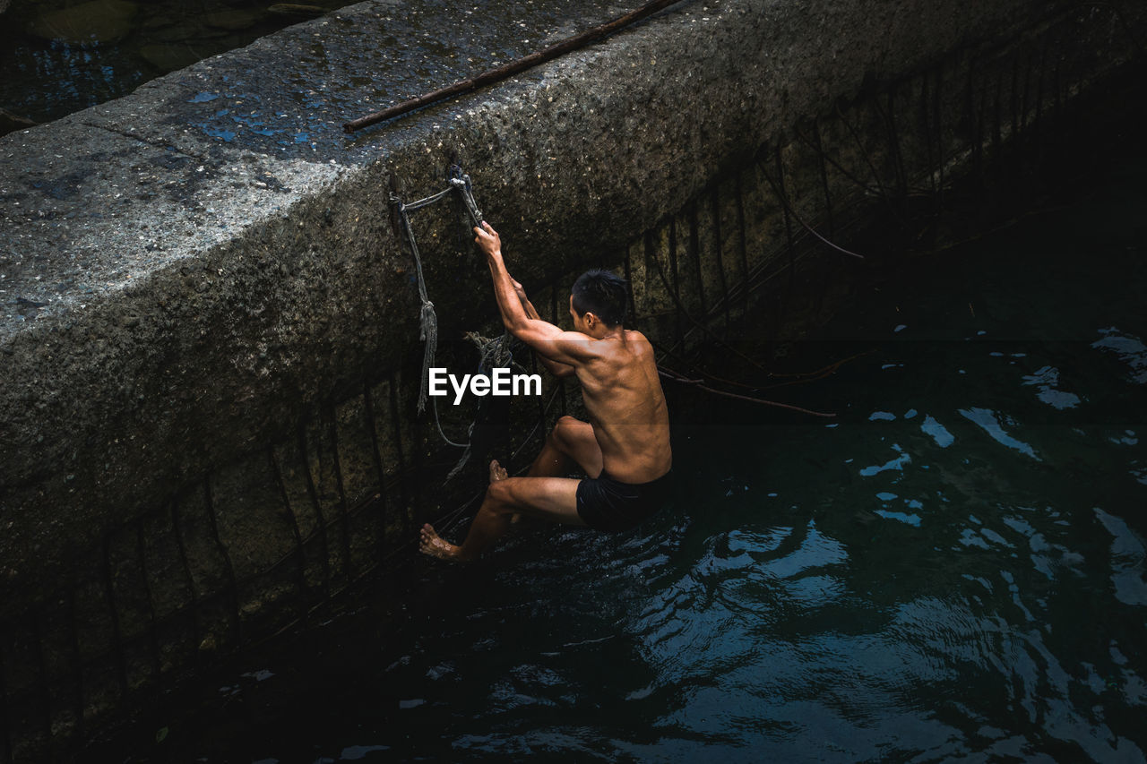 HIGH ANGLE VIEW OF MAN SWIMMING ON LAKE