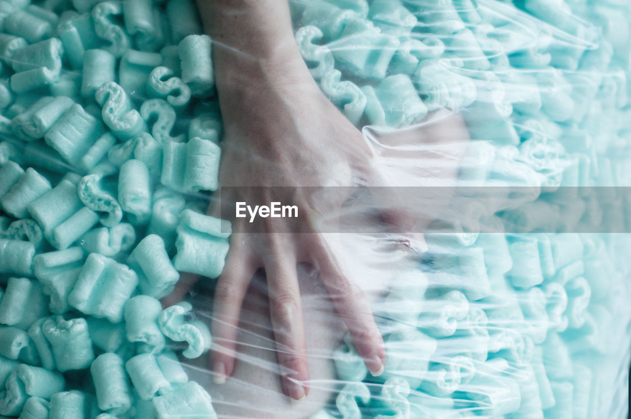 Cropped hand of woman amidst sweet food seen through plastic