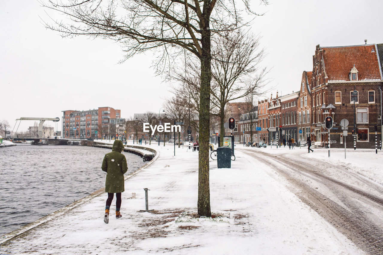 Rear view of woman walking on snow covered street