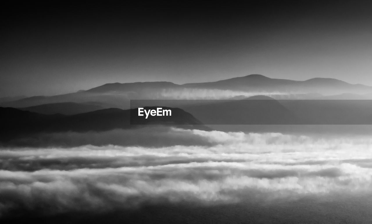 Scenic view of foggy landscape and mountains at dusk