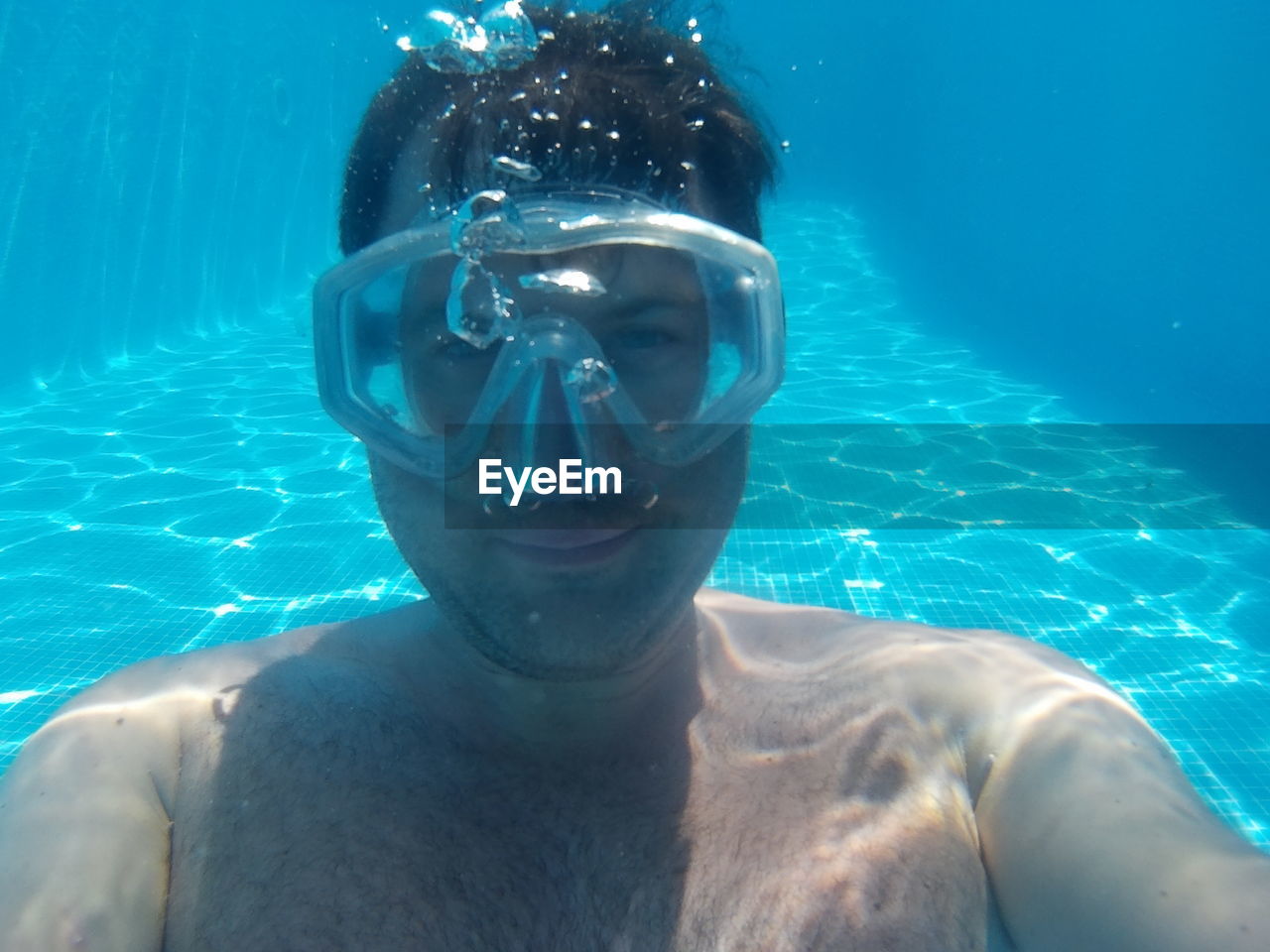 Portrait of shirtless man wearing scuba mask under swimming pool