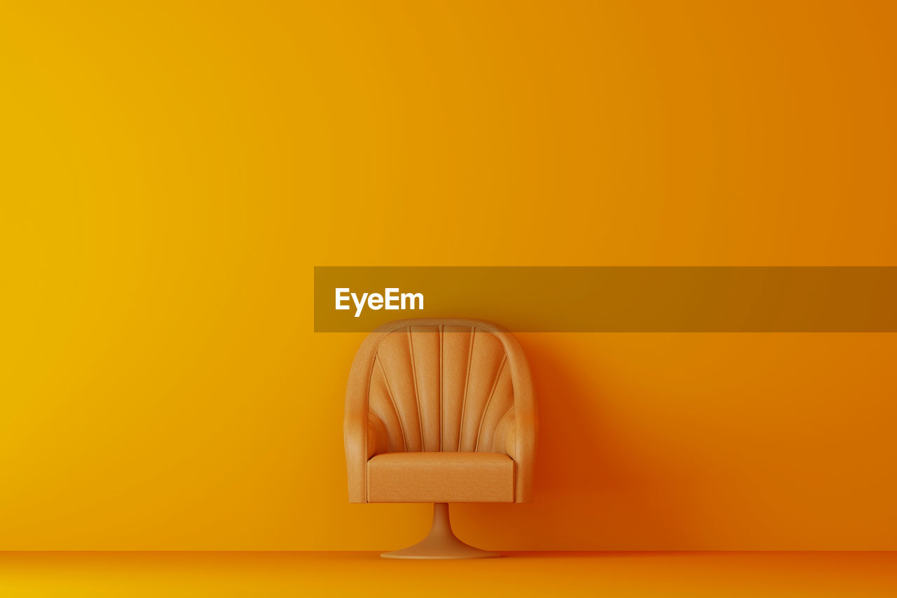 Empty chair against orange wall