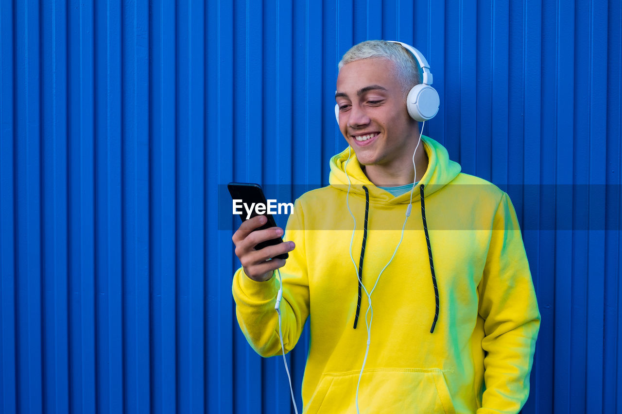 Young man with headphones against blue wall