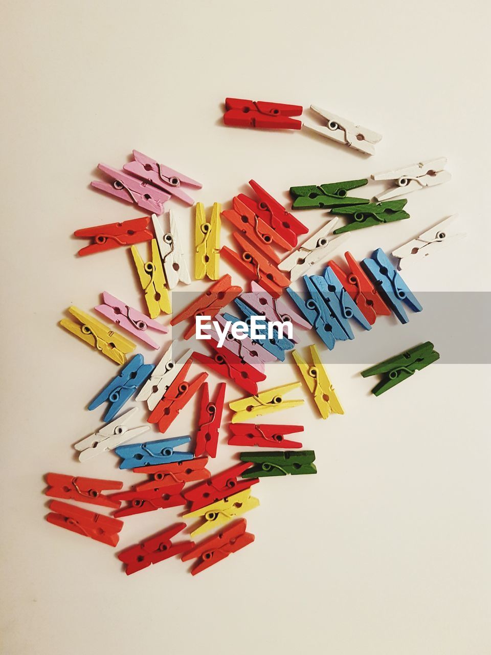 High angle view of colorful clothespins on white background