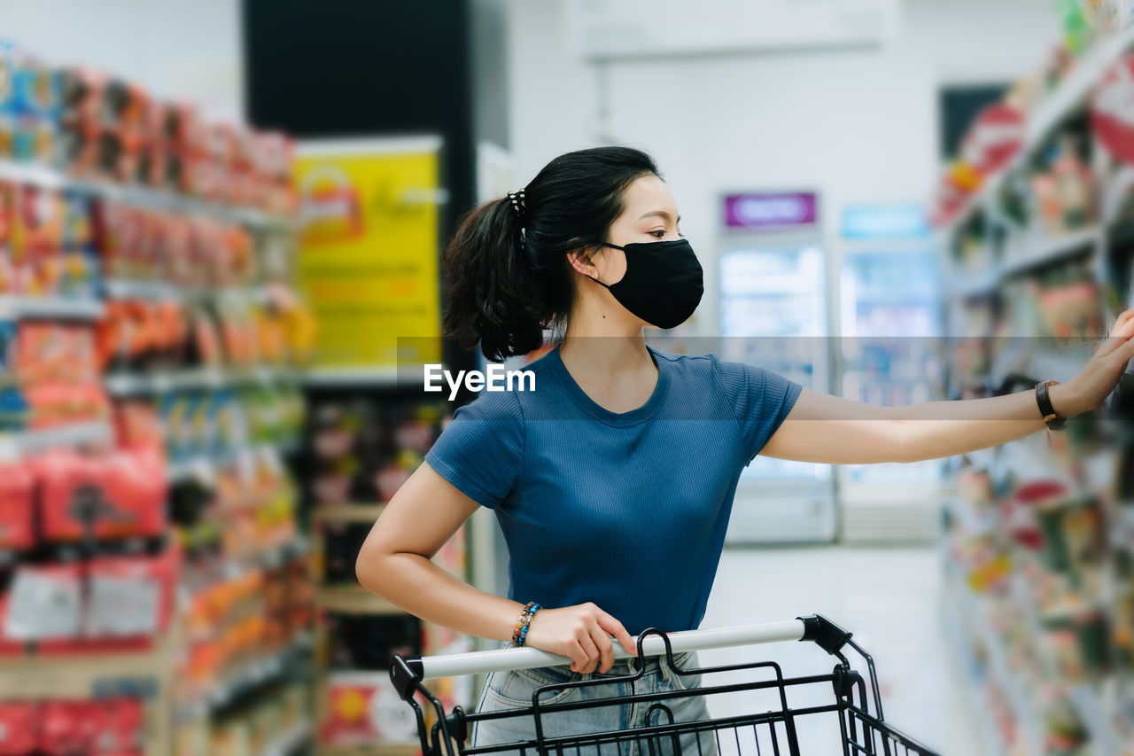 FULL LENGTH OF YOUNG WOMAN HOLDING STORE AT SHOP