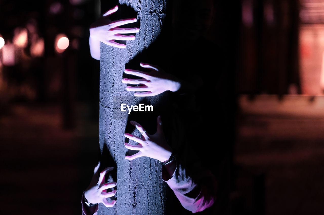 Cropped hand of women holding tree trunk outdoors