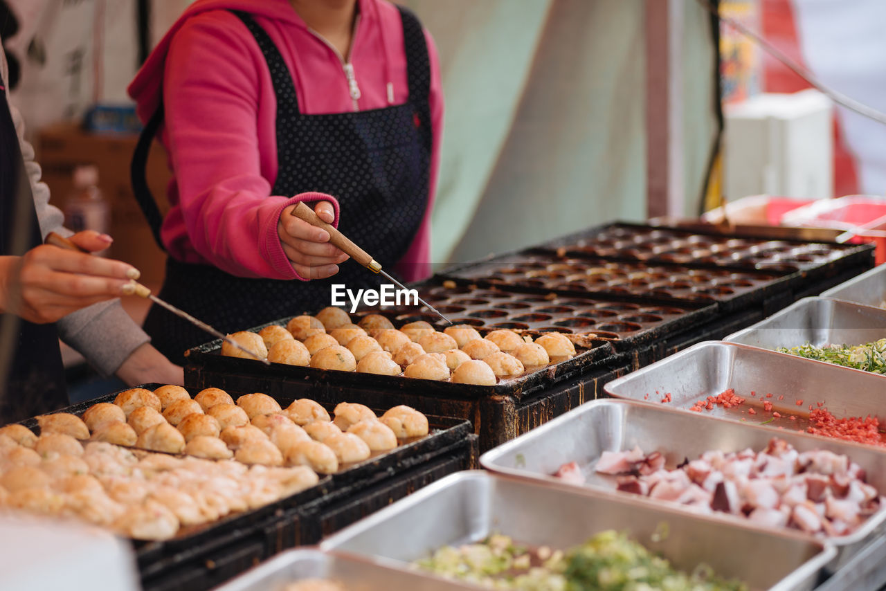 Midsection of woman preparing japanese street food at market