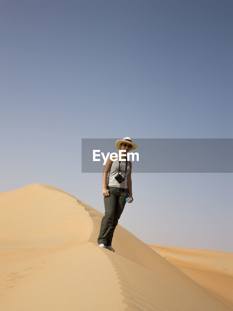 LOW ANGLE VIEW OF MAN STANDING ON SAND DUNE