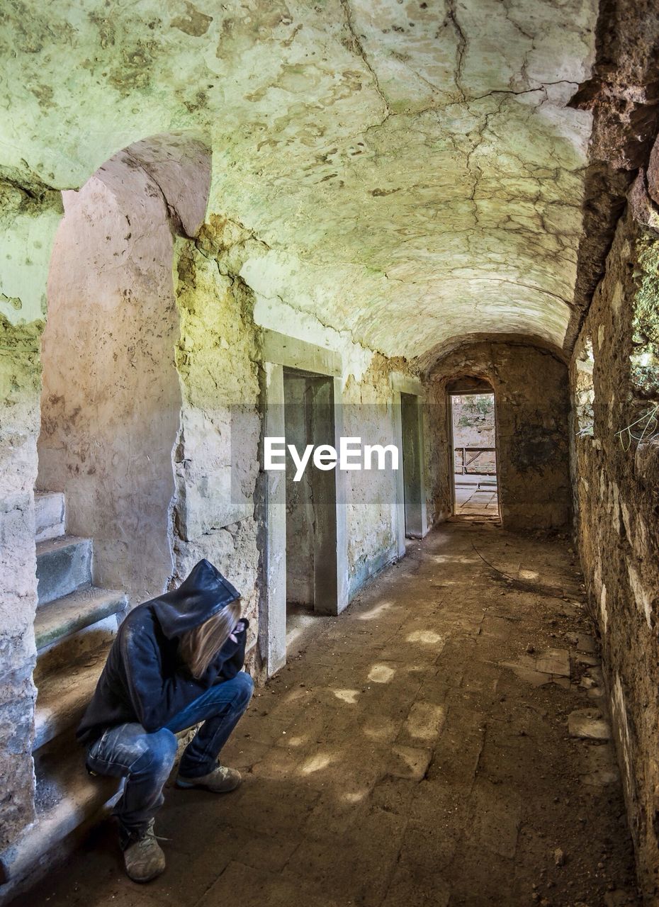 Woman sitting in abandoned corridor