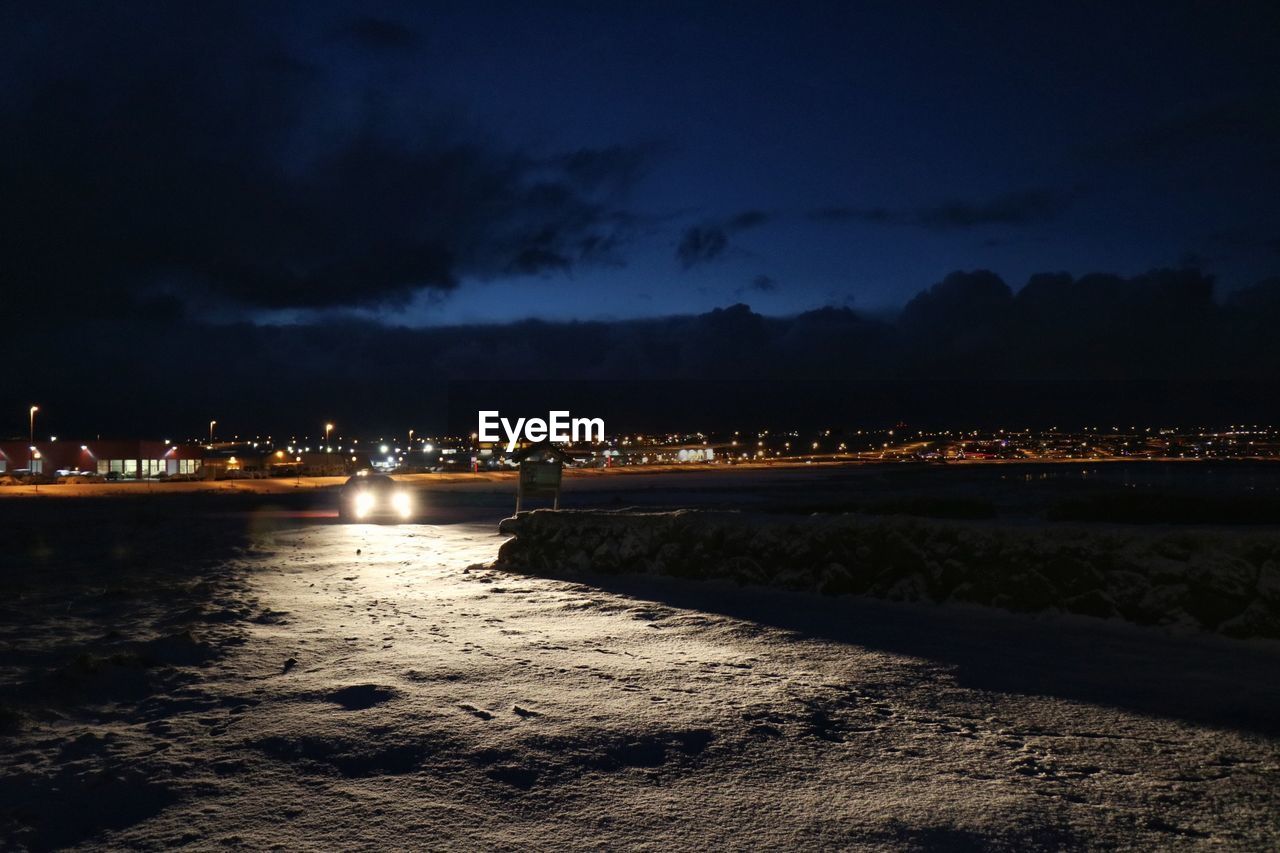 ILLUMINATED CITY BY SEA AT NIGHT