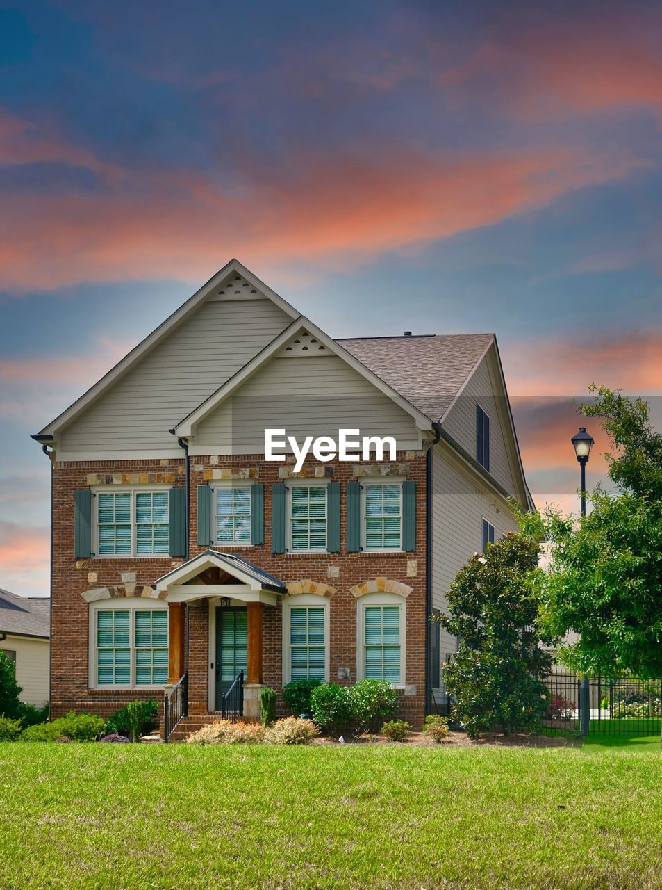 HOUSE ON FIELD BY BUILDING AGAINST SKY DURING SUNSET