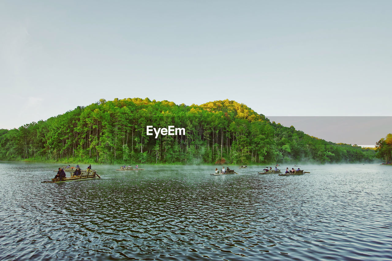 PEOPLE IN LAKE AGAINST SKY