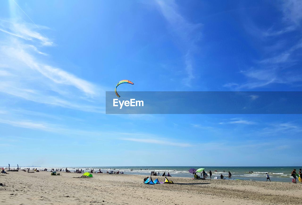 Scenic view of people on beach against sky