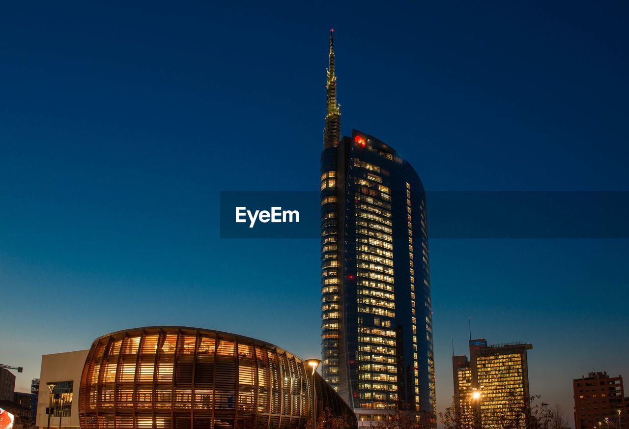 LOW ANGLE VIEW OF ILLUMINATED BUILDINGS AGAINST CLEAR BLUE SKY