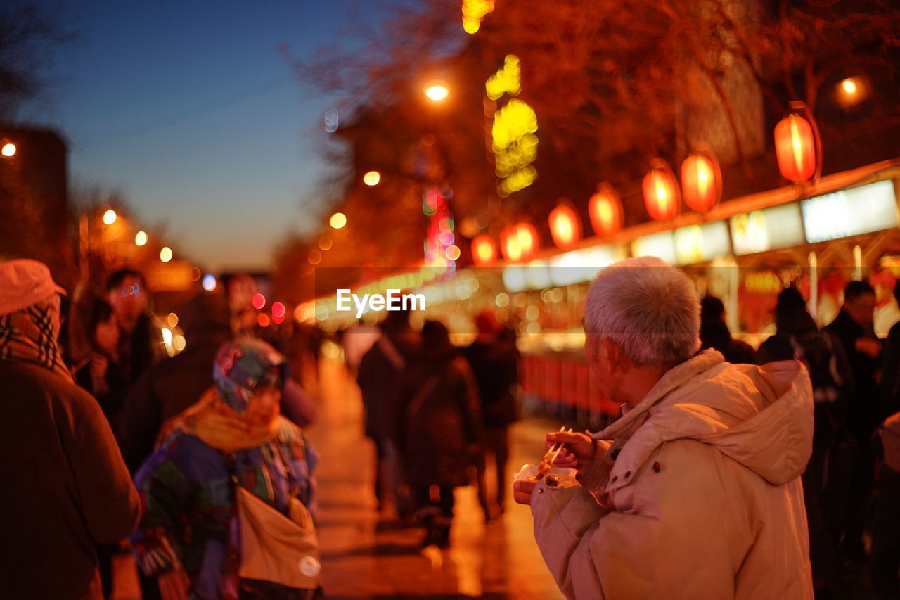 CROWD IN ILLUMINATED STREET